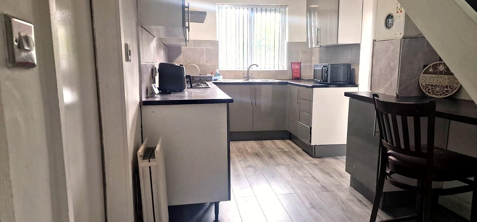 An open kitchen and dining space with grey units and wood-effect flooring