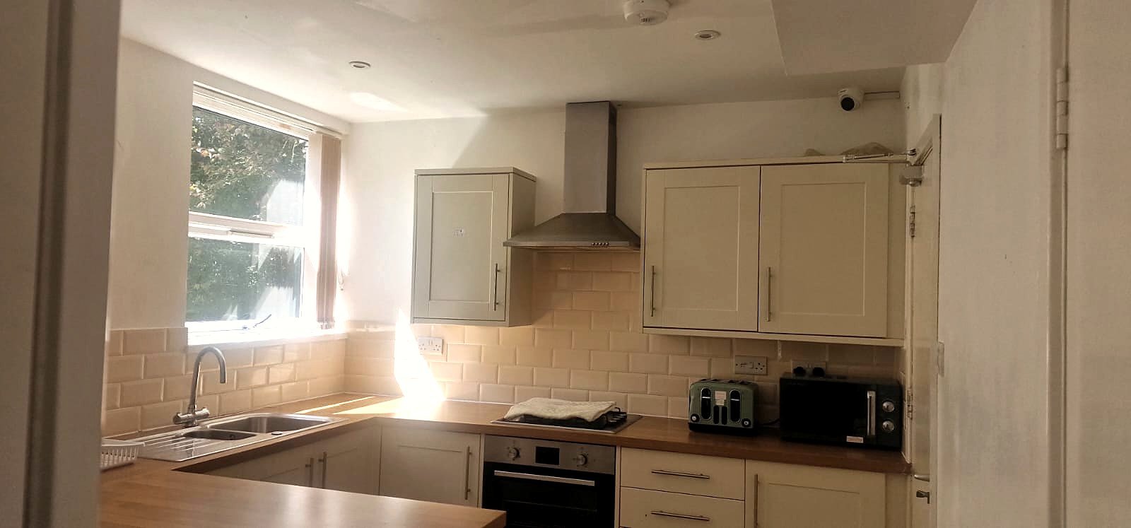A kitchen with oak worktops, oven and window over the sink