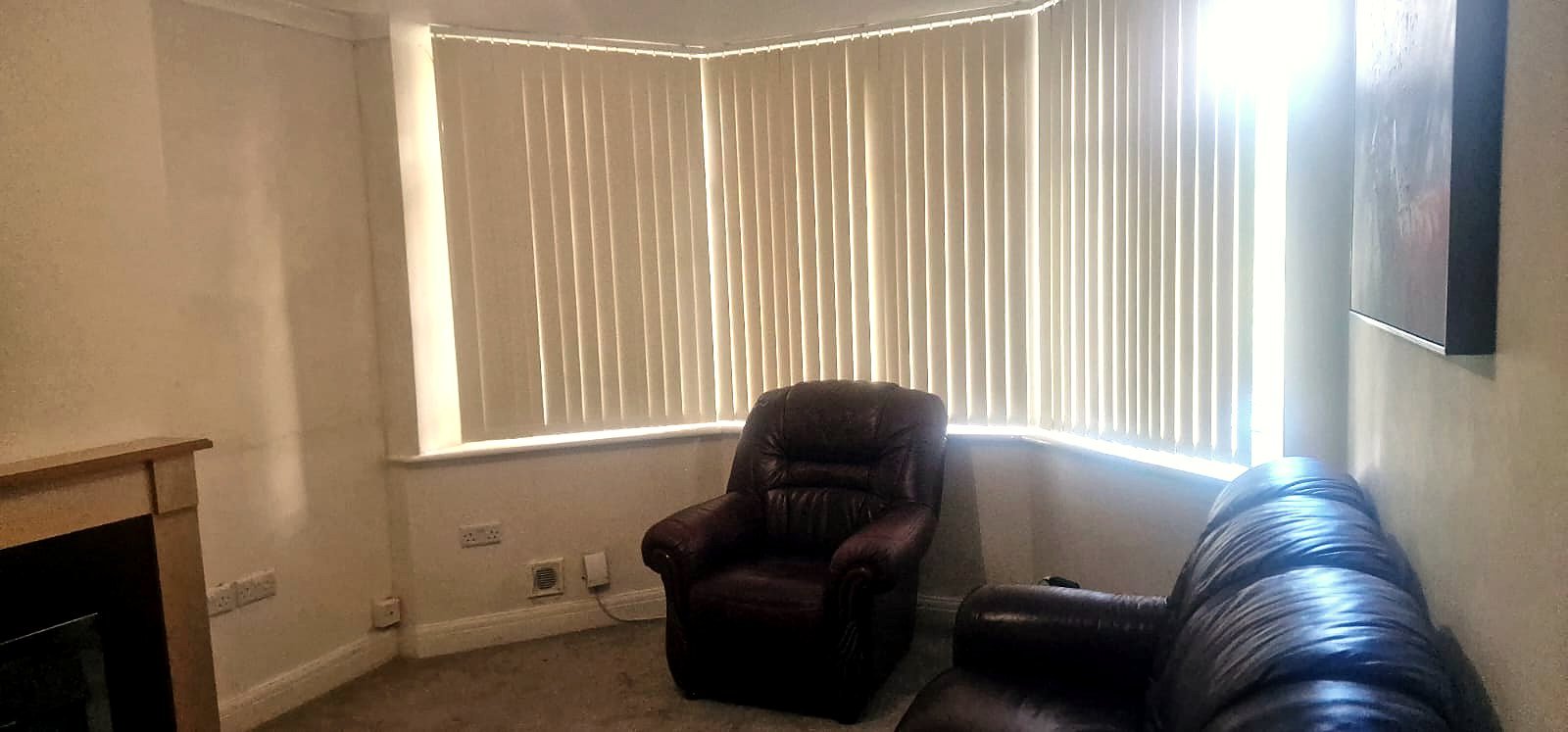 A lounge with leather sofas beneath a wide bay window